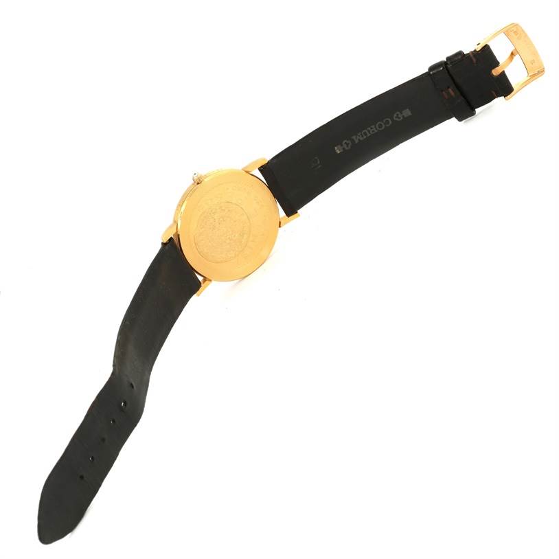 The image shows the back view of the Corum Coin Watch Men's Yellow Gold Champagne Dial Men's Yellow Gold Champagne Dial model, displaying its gold case and black leather strap with buckle.