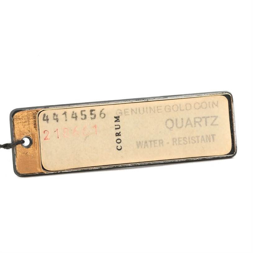 This image shows a close-up of a tag for the Corum Coin Watch Men's Yellow Gold Black Dial Men's Yellow Gold Black Dial model, indicating it's made of a genuine gold coin and is quartz and water-resistant.