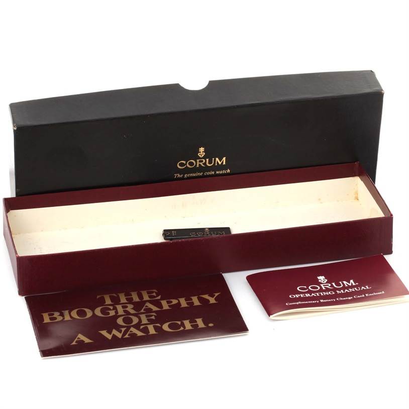 The image shows the packaging and booklets for the Corum Coin Watch Men's Yellow Gold Black Dial Men's Yellow Gold Black Dial model, including the box and manuals.