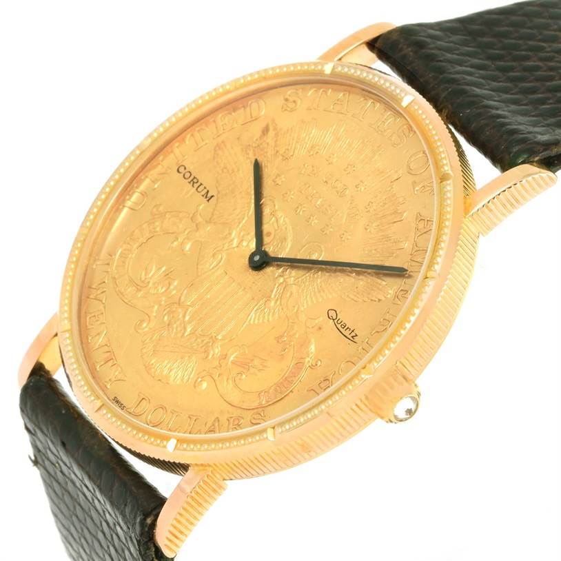 The image shows a Corum Coin Watch Men's Yellow Gold Black Dial Men's Yellow Gold Black Dial model, angled to display its gold face, black strap, and side crown.