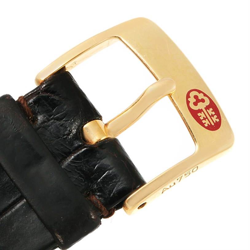 This is a close-up of the gold buckle and black leather strap of a Corum Coin Watch Men's Yellow Gold Black Dial Men's Yellow Gold Black Dial model.