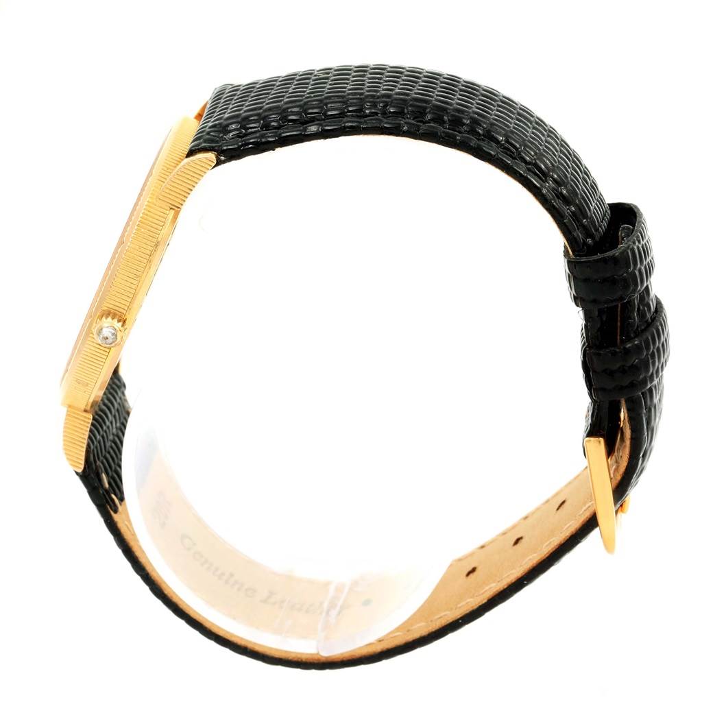 The image shows a side view of a Corum Coin Watch Men's Yellow Gold Black Dial Men's Yellow Gold Black Dial model, highlighting the gold case and black leather strap.