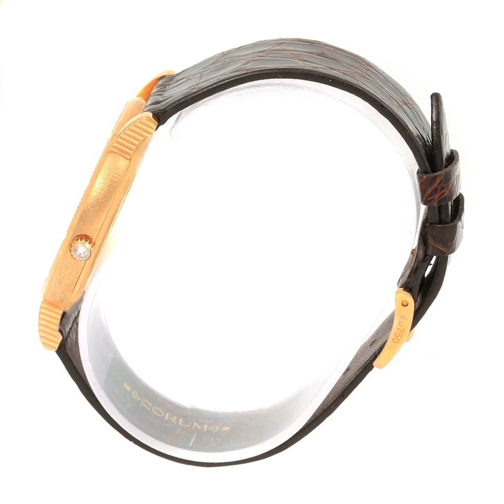 The image shows a side view of the Corum Coin Watch Men's Yellow Gold Black Dial Men's Yellow Gold Black Dial model, highlighting the case, the winding crown, and the leather strap.