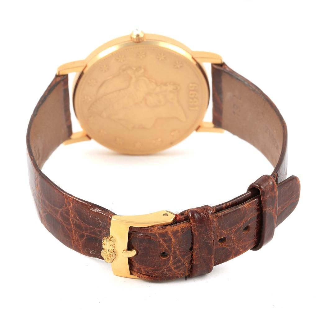 The image shows the back view of a Corum Coin Watch Men's Yellow Gold Black Dial Men's Yellow Gold Black Dial, displaying the coin design and leather strap with a gold buckle.