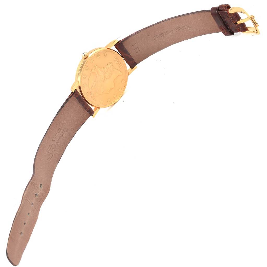 The image shows a Corum Coin Watch Men's Yellow Gold Black Dial Men's Yellow Gold Black Dial model from the back, featuring its leather strap and coin-designed case back.