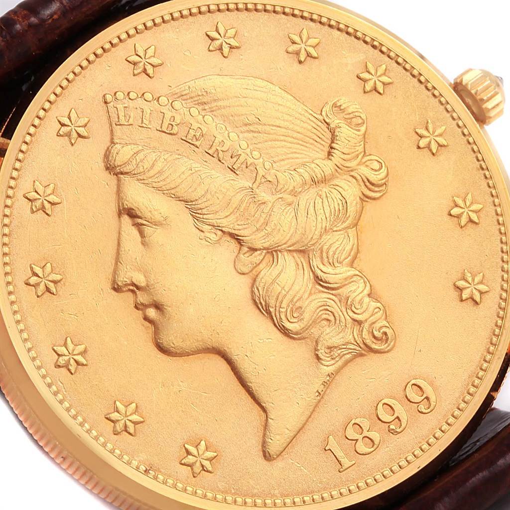 The image shows a close-up of the face of the Coin Watch model by Corum, highlighting its detailed coin design and part of the crown.