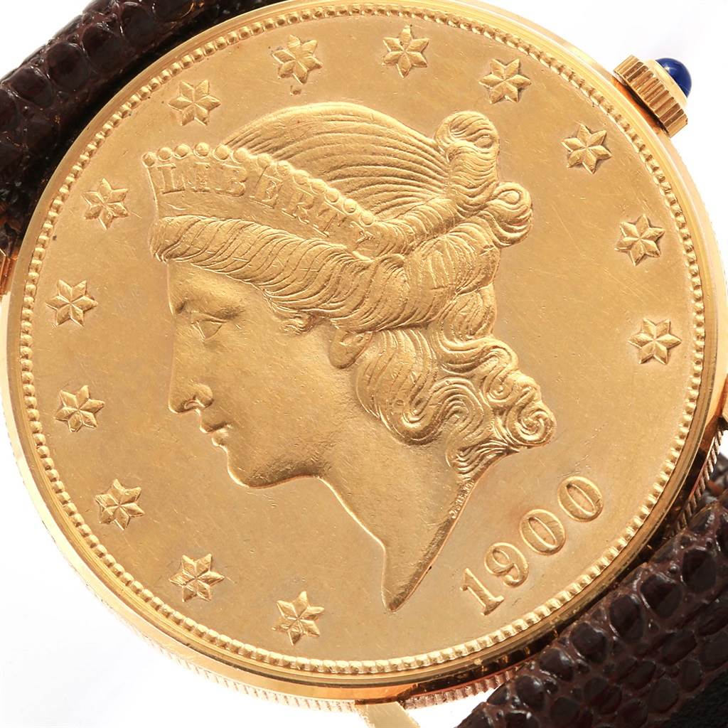 The image shows the face of a Corum Coin Watch Men's Yellow Gold Black Dial Men's Yellow Gold Black Dial model, featuring a gold coin design from a front angle with part of the strap visible.