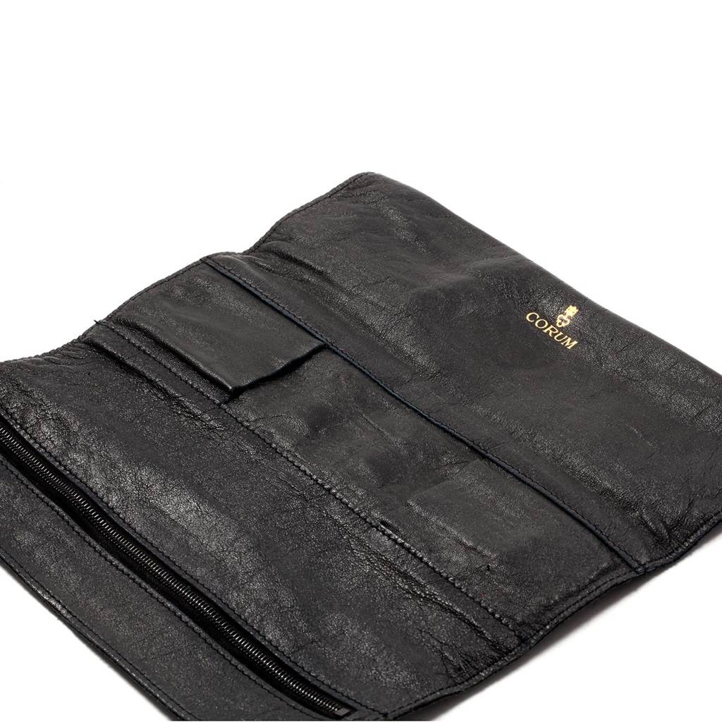 The image shows a black leather accessory pouch with the Corum logo as a part of the Coin Watch model.