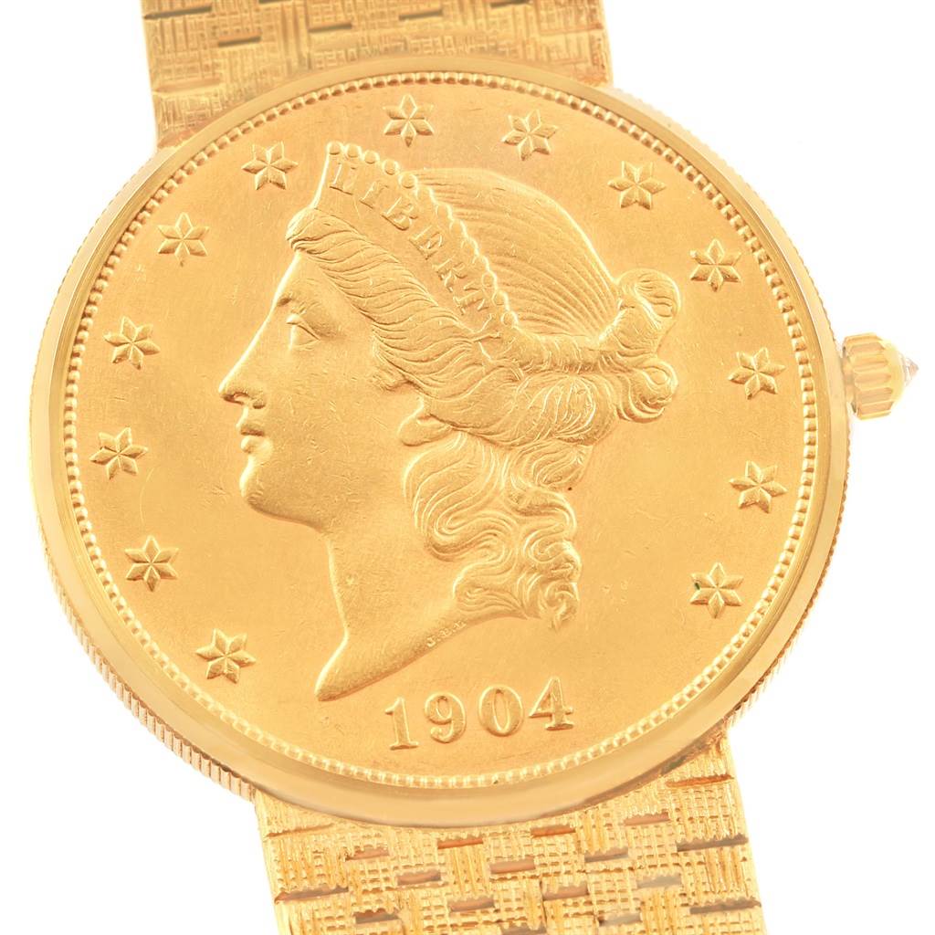 The image shows a Corum Coin Watch Men's Yellow Gold Black Dial Men's Yellow Gold Black Dial model from a top-down angle, highlighting its coin-like face featuring Lady Liberty and the year 1904.