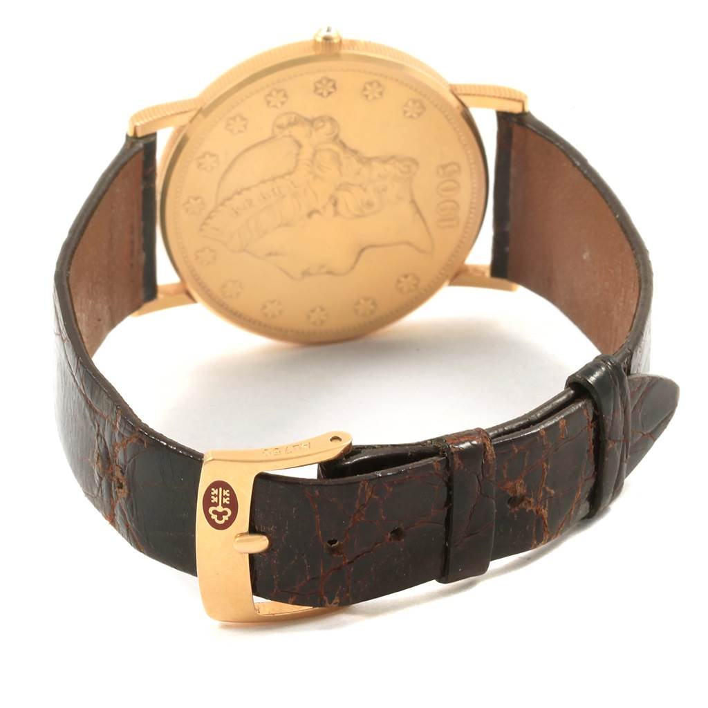 The Coin Watch model by Corum is shown from the rear, displaying the detailed coin design and leather strap with a golden buckle.