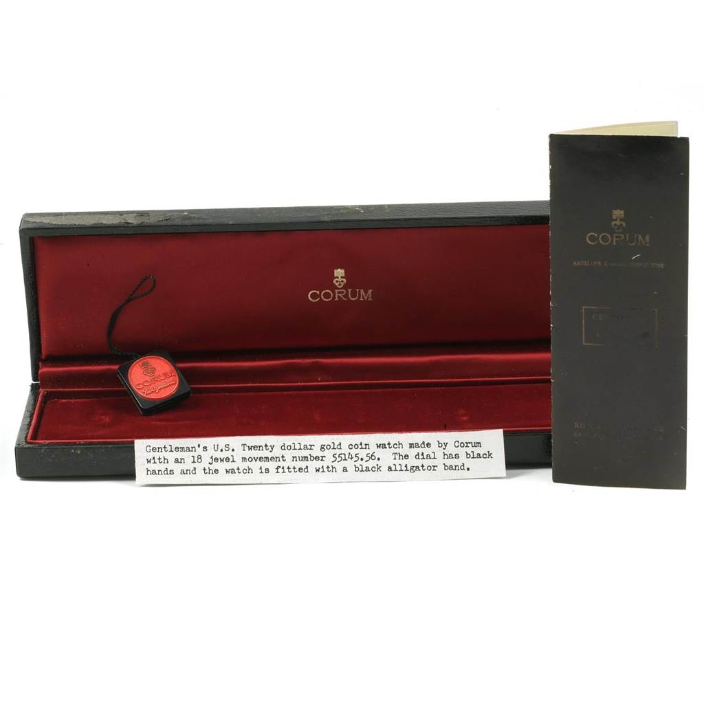 The image shows the packaging and accessories for a Corum Coin Watch Men's Yellow Gold Black Dial Men's Yellow Gold Black Dial model, including a box, tag, and documentation.