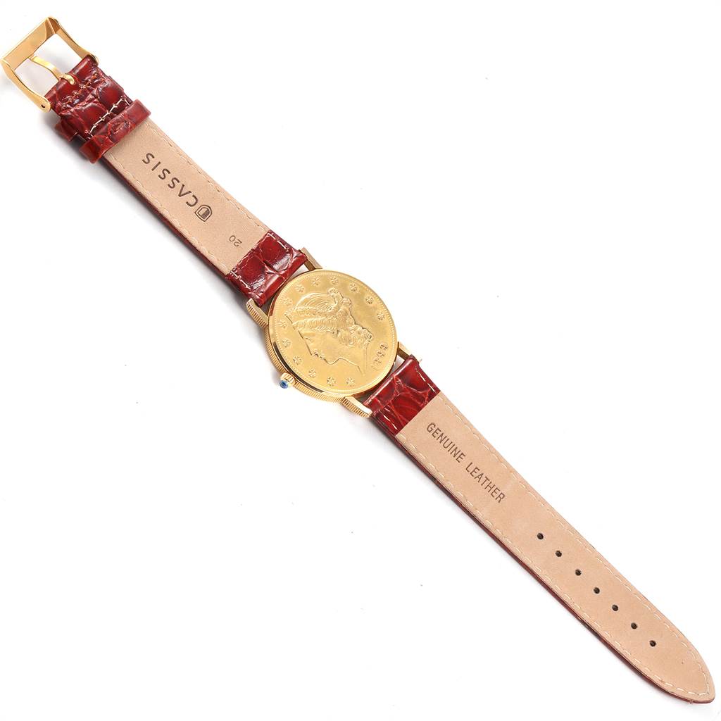 This image shows a Corum Coin Watch Men's Yellow Gold Black Dial Men's Yellow Gold Black Dial model laid flat, displaying its gold coin dial and red leather strap with buckle.
