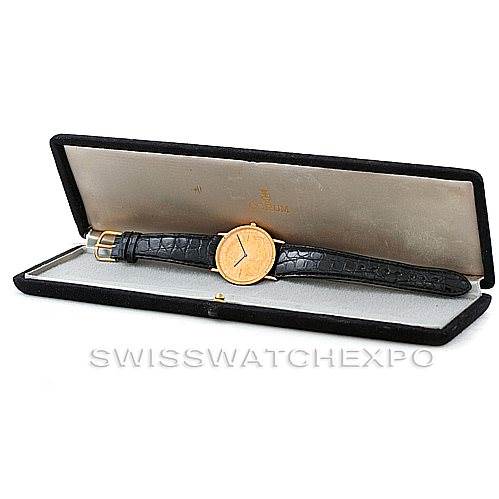 The image shows a Corum Vintage watch in its box, displaying the black leather strap and the gold case from a side angle.