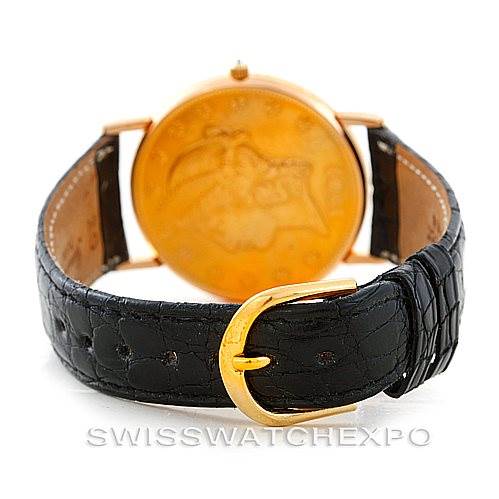 The image shows the rear view of a Vintage Corum watch, featuring a gold case back and a black leather strap with a gold buckle.