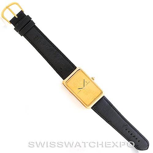 The image shows a top-down view of a vintage Corum watch with a rectangular gold face and a black leather strap.