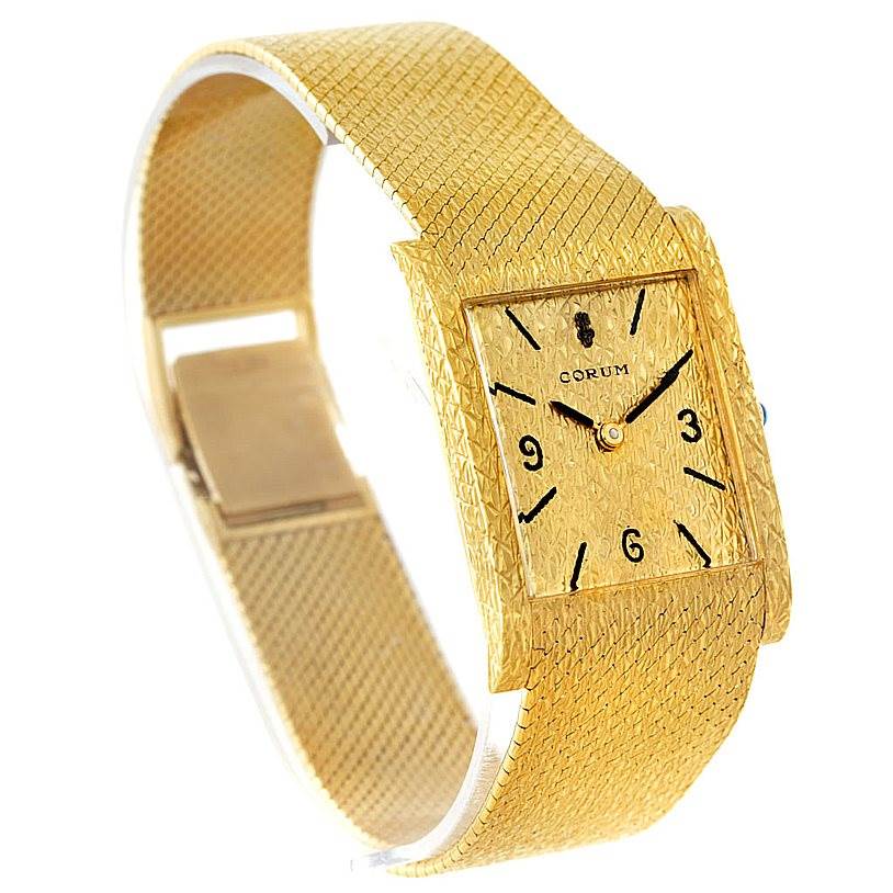 This image shows a vintage Corum watch angled slightly to the right, showcasing its gold-textured band and rectangular face.
