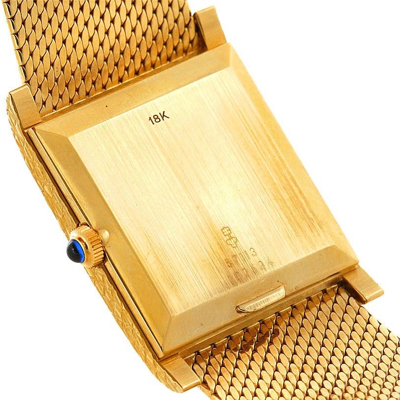 The image shows the back and side of a vintage Corum watch case and part of the gold mesh strap.