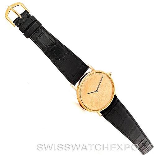 This image shows a top-down view of a Vintage Corum watch, highlighting its black leather strap and gold-tone case with a textured dial.