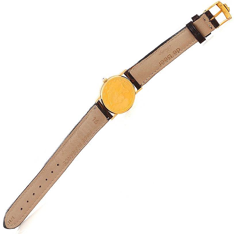 The image shows a top-down view of the Ladies 18K Yellow Gold 10 Dollars Coin Watch by Corum Women's Yellow Gold Black Dial Women's Yellow Gold Black Dial, displaying the full strap and coin-shaped watch face.