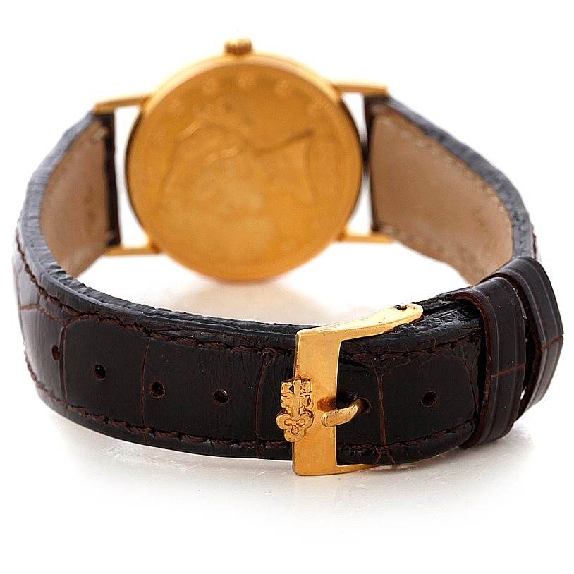 The image shows a rear view of the Corum Women's Yellow Gold Black Dial Women's Yellow Gold Black Dial Ladies 18K Yellow Gold 10 Dollars Coin Watch, focusing on the buckle and case back.