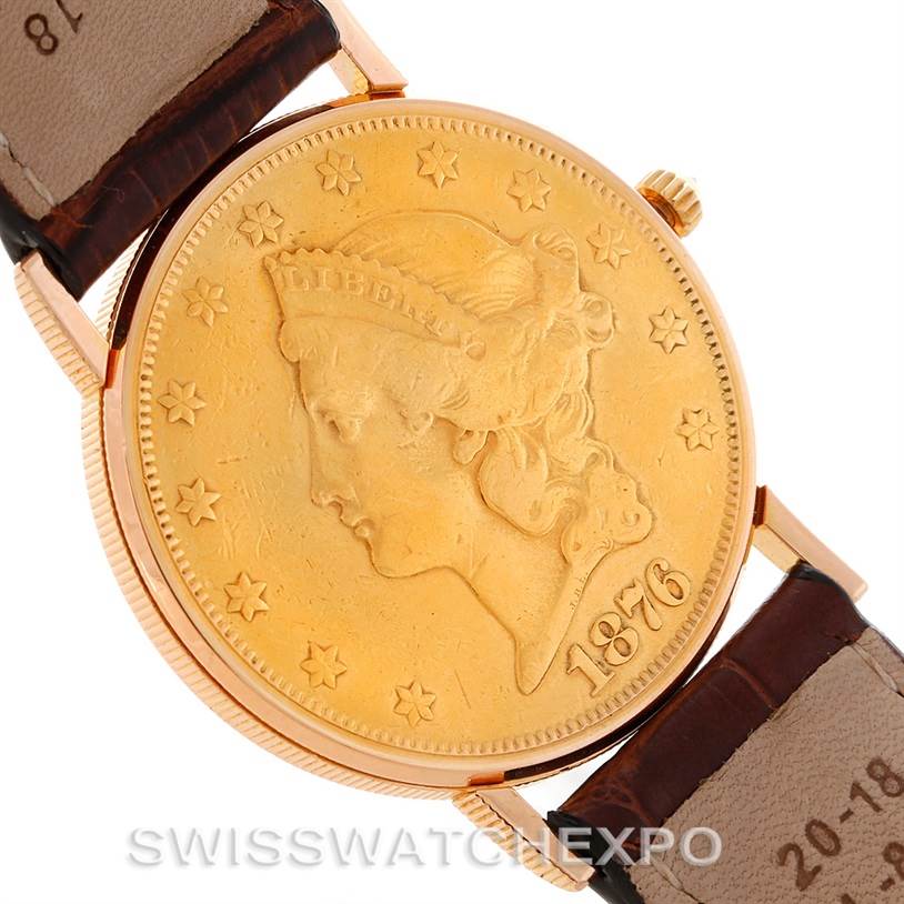 The image shows a face view of the Corum Coin Watch Men's Yellow Gold Black Dial Men's Yellow Gold Black Dial model, displaying its coin-shaped dial and part of the leather strap.