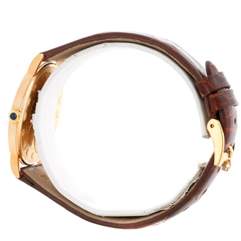 The image shows a side view of a Corum Coin Watch Men's Yellow Gold Black Dial Men's Yellow Gold Black Dial model, highlighting the gold case, crown, and brown leather strap.