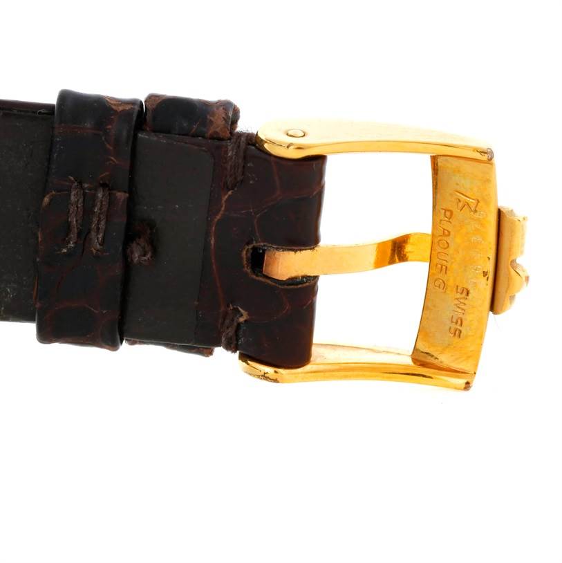 The Corum Coin Watch Men's Yellow Gold Black Dial Men's Yellow Gold Black Dial model image shows a close-up of the leather strap and gold buckle.