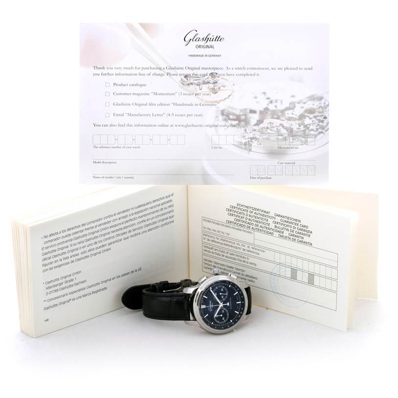 The image shows a Glashutte Original Senator watch with black leather strap, flanked by open paperwork and documentation.