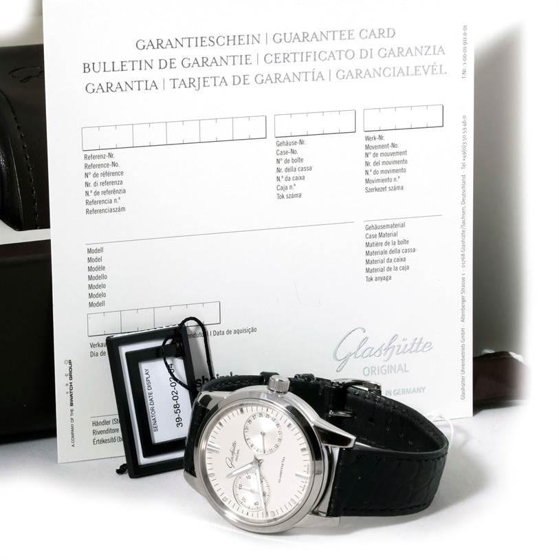 The image shows a Glashütte Senator watch at a slight angle, with its warranty card and tag visible in the background.