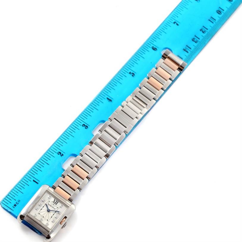 The image shows a silver and rose gold Cartier Tank Anglaise WT100024 Women's Steel and Gold (two tone) Silver Dial WT100024 Women's Steel and Gold (two tone) Silver Dial watch laid flat next to a blue ruler.