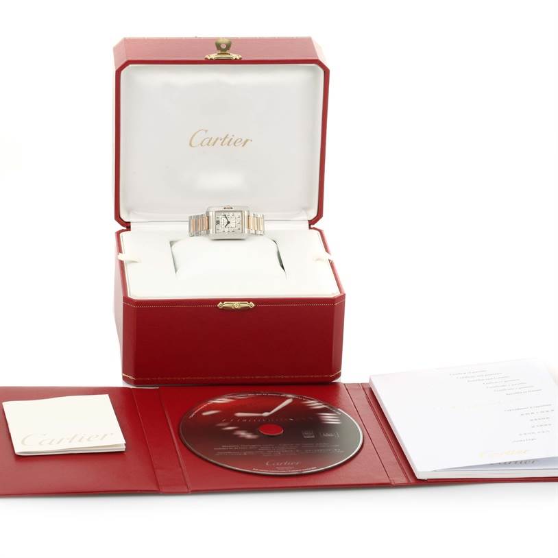 The Cartier Tank Anglaise WT100024 Women's Steel and Gold (two tone) Silver Dial WT100024 Women's Steel and Gold (two tone) Silver Dial watch is shown in its open box, with included accessories like a manual and a CD displayed in front.
