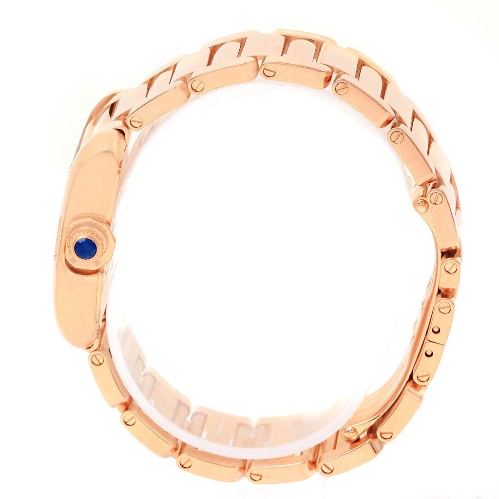 The Tank Anglaise by Cartier is shown from a side angle, highlighting its rose gold bracelet and crown with a blue cabochon.