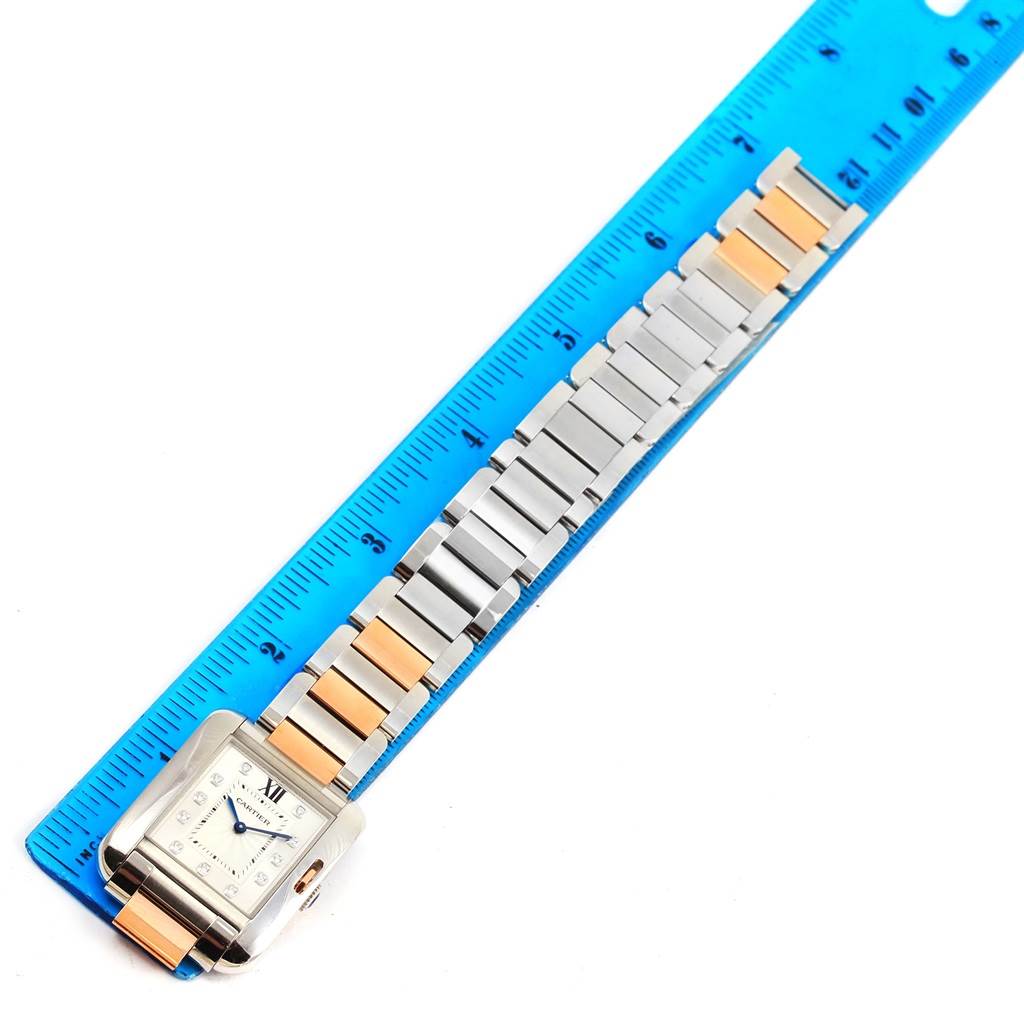 The image shows a Cartier Tank Anglaise WT100032 Women's Steel and Gold (two tone) Silver Dial WT100032 Women's Steel and Gold (two tone) Silver Dial watch placed next to a ruler, displaying its face and metal bracelet.