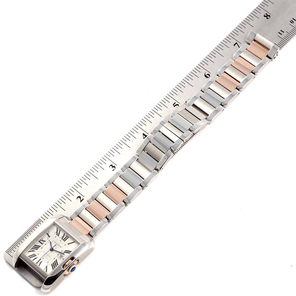 This image shows the Tank Anglaise model by Cartier watch laid flat next to a ruler, displaying the watch's band and face.