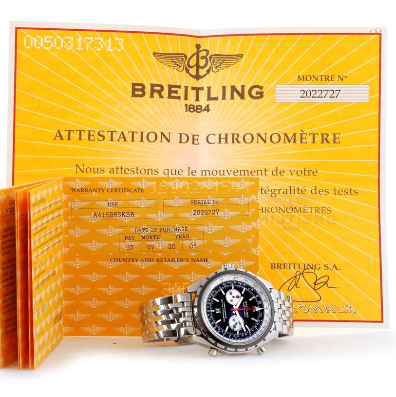 The image shows a Breitling Chronomatic A41360 Men's Stainless Steel Black Dial A41360 Men's Stainless Steel Black Dial watch with warranty papers and a certificate, displayed from a front angle on a flat surface.