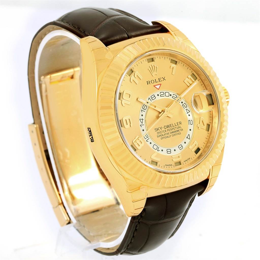 The image shows a close-up angled view of the Rolex Sky-Dweller 326138 Men's Yellow Gold Champagne Dial 326138 Men's Yellow Gold Champagne Dial watch, highlighting its gold dial, bezel, and dark leather strap.