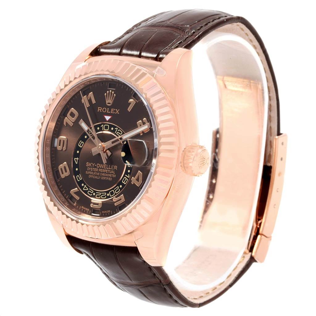 The Rolex Sky-Dweller 326135 Men's Rose Gold Brown Dial 326135 Men's Rose Gold Brown Dial watch is shown at a three-quarter angle, highlighting its dial, bezel, and brown leather strap.