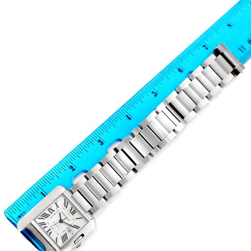 The image shows the front angle of a Cartier Tank Anglaise W5310009 Men's Stainless Steel Silver Dial W5310009 Men's Stainless Steel Silver Dial watch alongside a blue ruler, displaying its bracelet and face.