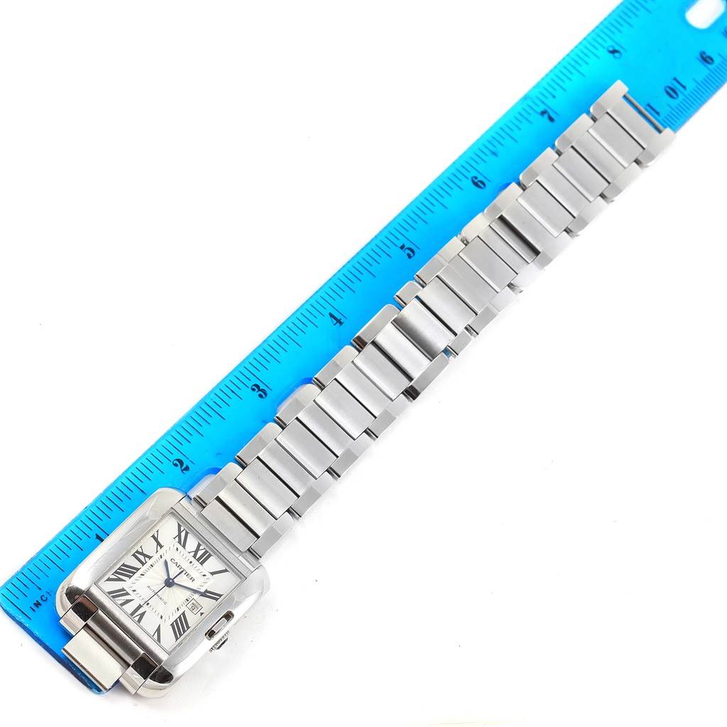 The Cartier Tank Anglaise W5310009 Men's Stainless Steel Silver Dial W5310009 Men's Stainless Steel Silver Dial watch is shown from the top view, highlighting the face and metal bracelet next to a blue ruler for scale.
