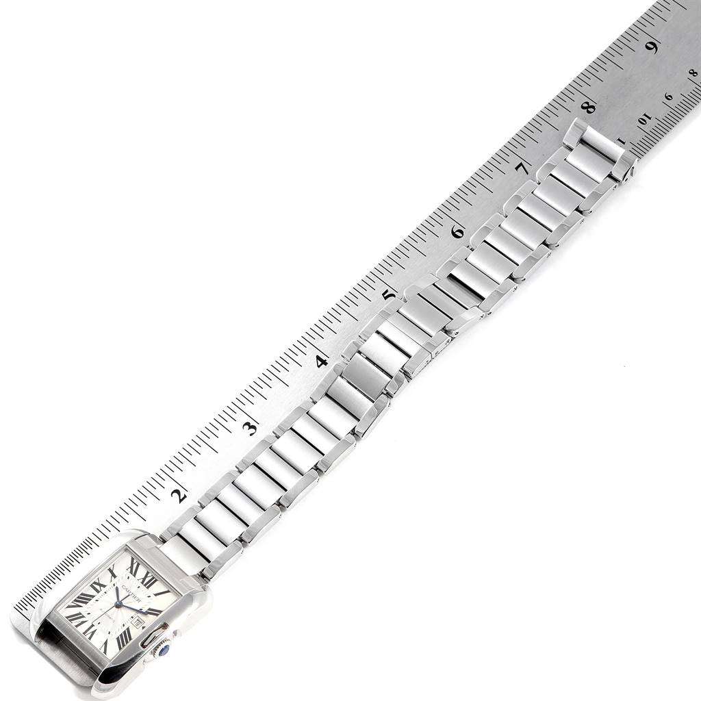 The Cartier Tank Anglaise W5310009 Men's Stainless Steel Silver Dial W5310009 Men's Stainless Steel Silver Dial watch is shown from an overhead angle, displaying the face and full length of the metal band beside a ruler.