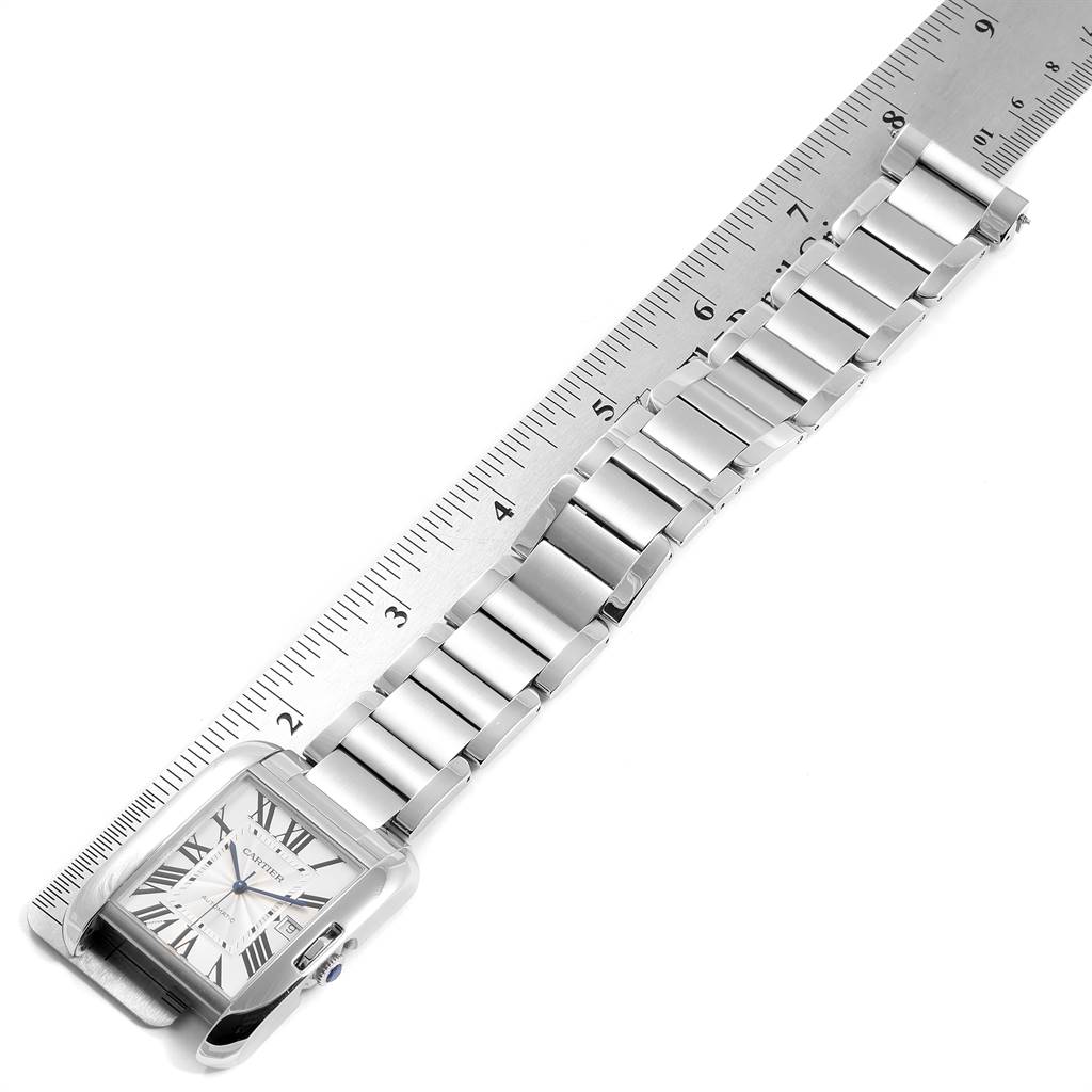 The Cartier Tank Anglaise W5310008 Men's Stainless Steel Silver Dial W5310008 Men's Stainless Steel Silver Dial watch is shown from a top angle, highlighting the face and bracelet next to a ruler.