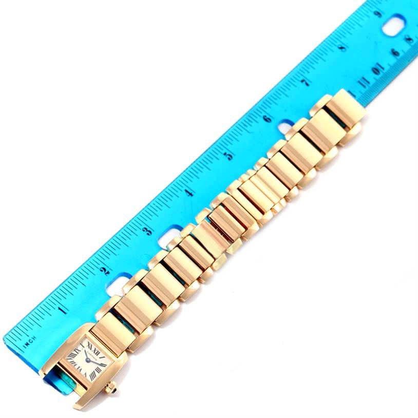 The Cartier Tankissime W650037H Women's Yellow Gold Silver Dial W650037H Women's Yellow Gold Silver Dial watch is shown flat with its bracelet next to a blue ruler for scale.