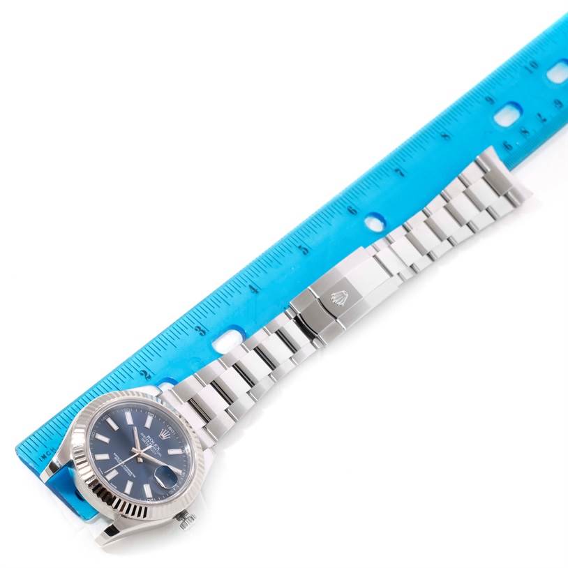 The Rolex Datejust 41 116334 Men's Stainless Steel Blue Dial 116334 Men's Stainless Steel Blue Dial watch is shown with a ruler, displaying the full band and part of the dial from a top-down angle.