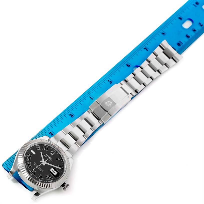 The Rolex Datejust 41 116334 Men
s Stainless Steel Grey Dial 116334 Men
s Stainless Steel Grey Dial watch is shown from above, displaying the face, fluted bezel, bracelet, and clasp with a blue ruler for scale.