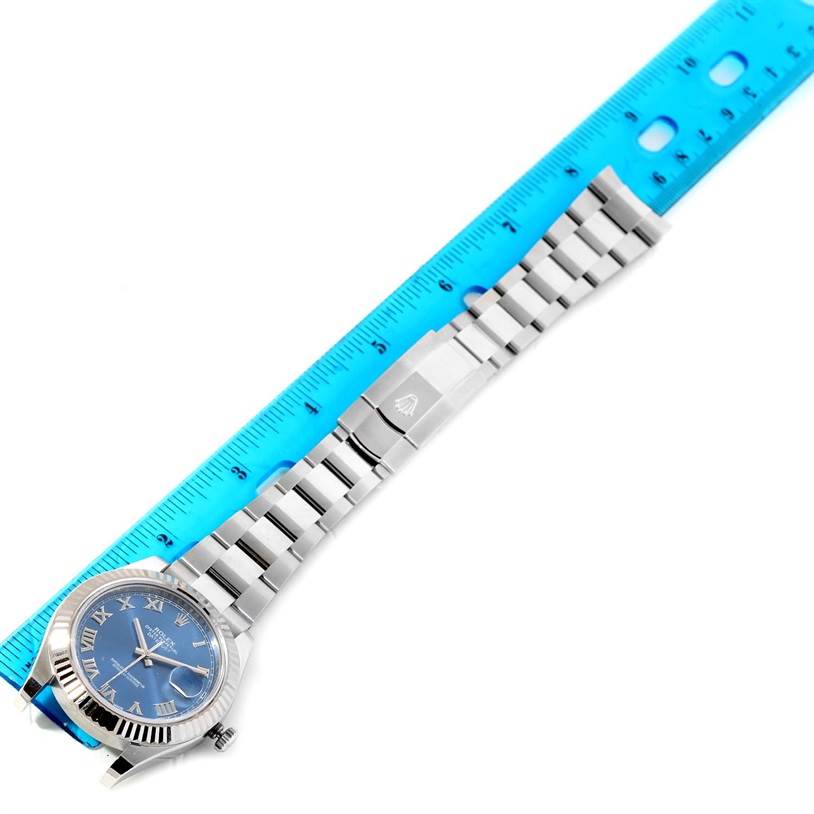 The Rolex Datejust 41 116334BLRO Men's Stainless Steel Blue Dial 116334BLRO Men's Stainless Steel Blue Dial watch is shown from a top-down angle with a blue ruler beside it, highlighting its bracelet and clasp.