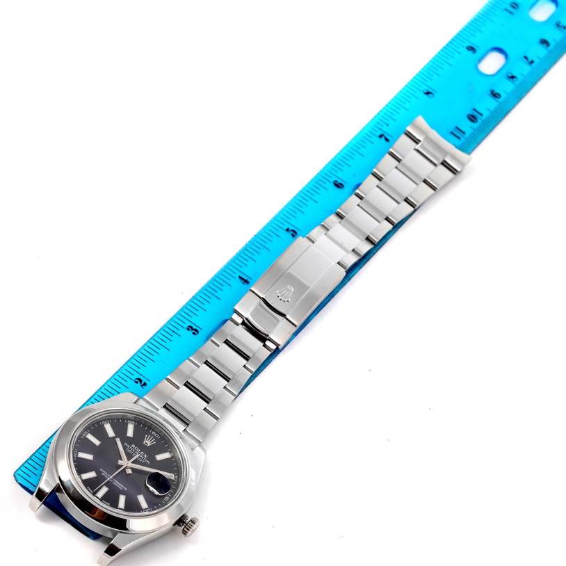 The image shows a Rolex Datejust 41 116300 Men's Stainless Steel Black Dial 116300 Men's Stainless Steel Black Dial watch at an angle displaying its face, bracelet, and clasp beside a blue ruler.