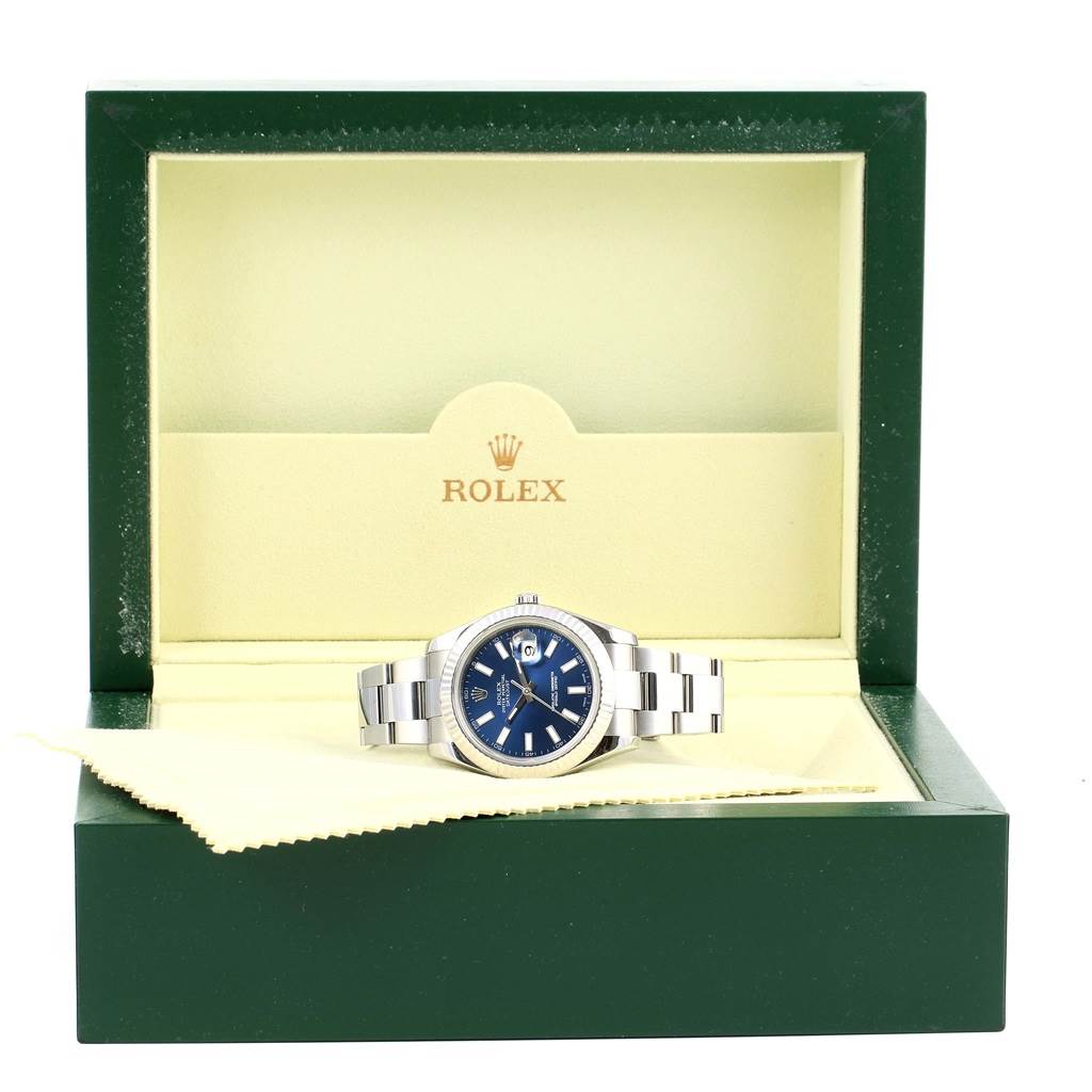 The Rolex Datejust 41 116334 Men's Stainless Steel Blue Dial 116334 Men's Stainless Steel Blue Dial watch is displayed at a slight front angle inside its open green box, revealing its blue dial and metal bracelet.