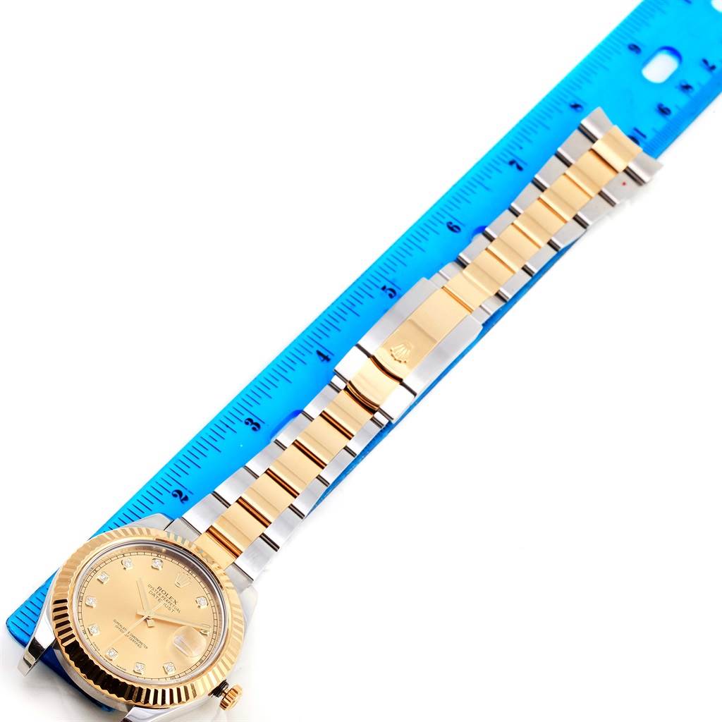 The Rolex Datejust 41 116333 Men's Steel and Gold (two tone) Champagne Dial 116333 Men's Steel and Gold (two tone) Champagne Dial watch is shown from an overhead angle next to a blue ruler, highlighting the dial, bezel, crown, and bracelet.