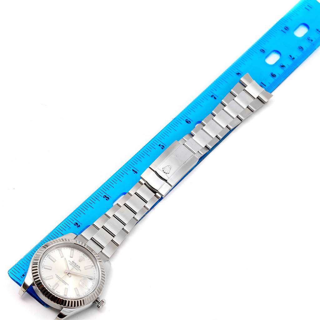 The Rolex Datejust 41 116334 Men's Stainless Steel Silver Dial 116334 Men's Stainless Steel Silver Dial watch is shown from a top-down angle with its dial, bracelet, and clasp visible next to a blue ruler.