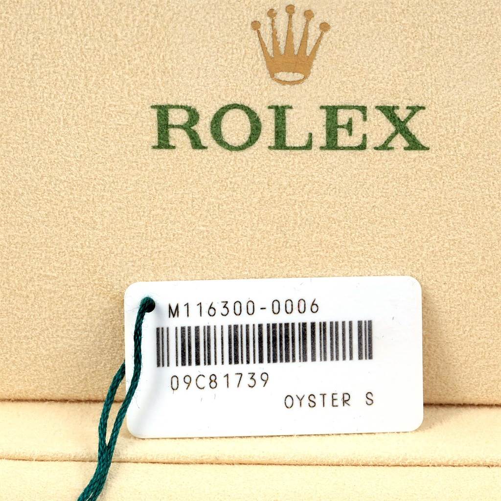 The image shows a Rolex tag with model information and a barcode, placed on a fabric background with the Rolex logo.